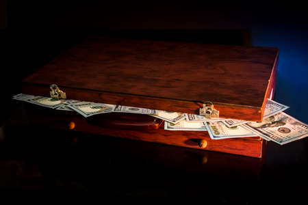 Dark suitcase full of dollar isolated on black.の写真素材