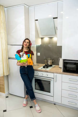 Young wife cleaning cooker hood with rag and detergent in kitchen. Housekeeping concept.の写真素材