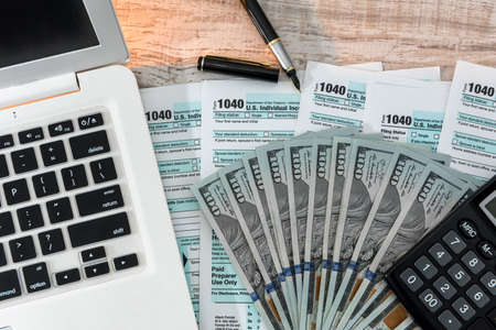 us 1040 tax form with pen, dollar and laptop at office. tax time. accounting conceptの写真素材