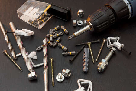 set of tools on the table, a screwdriver with a set of drill bits and screws with bolts. all for...