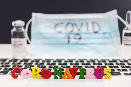 2019 Coronavirus write on vedical mask with vaccine in ampoule and laptop. Worldwide epidemic. Virus vaccine search conceptの写真素材