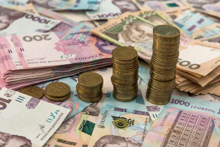 500 and 1000 bill ukraine money as background. gold coin lying on pile of grivna. money caonceptの写真素材