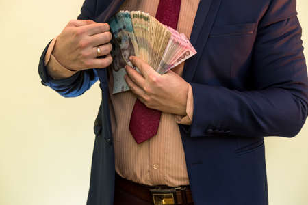 Business man hiding pack of Ukraine in suit pocket. The concept of corruption and fraud. UAH 1000...