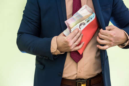 businessman receives money as a bribe in envelope. a man gives a whole bunch of hryvnia Ukrainian money in an envelopeの写真素材