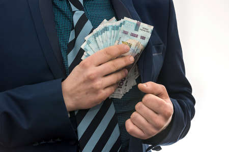 businessman takes a pack of Ukrainian money as a bribe and hides in his pocket in a jacket. Corruption and a trick. UAH. 1000 new banknoteの写真素材