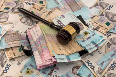 wooden hammer on ukraine money as background. 500 and 1000 new uah grivna. legal or save concept