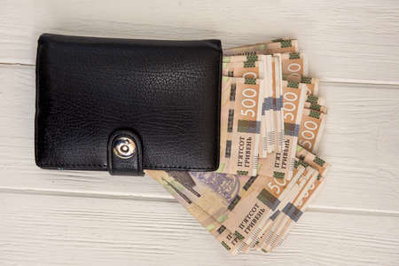 UAH, Black men's wallet is full of money. UAH Money of Ukraine 1000 and 500 banknotes on desk. money...
