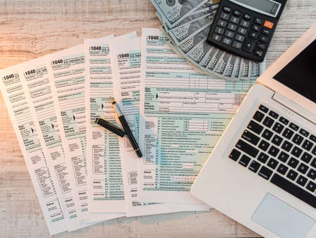 us 1040 tax form with pen, dollar and laptop at office. tax time. accounting conceptの写真素材