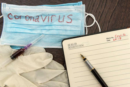 Search virus vaccine coronavirus as danger diseaseas concept. Fasical mask with text covid 19and syring with blood. Epidemicの写真素材