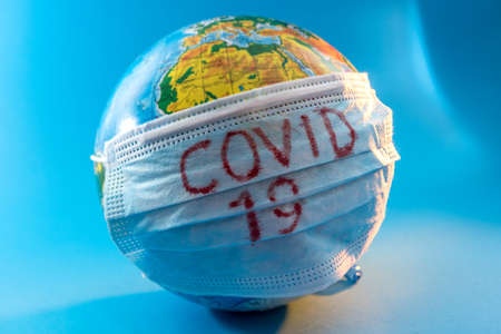 globe of planet dressed a medical mask with text Covid -19 worldwide epidemic. Coronavirus and quarantine planet infection pandemic conceptの写真素材