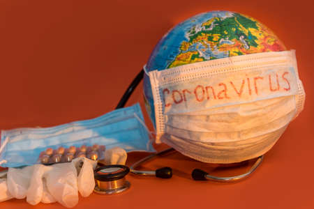 2019-nCoV earth globe with stethoscope and mask, virus concept. Coronavirus as text on surgical mask protection and oxygen face mask.の写真素材