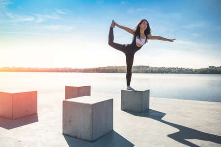 Sportive young woman doing fitness exercises near the lake at daytime. Healthy lifestyle conceptの写真素材