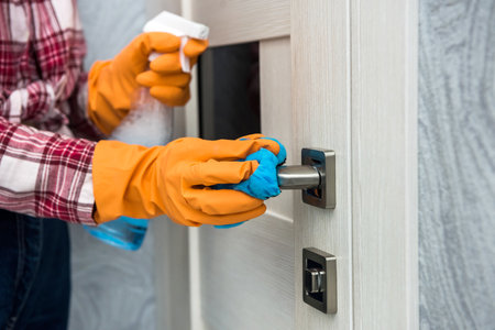 woman in protective gloves holding a spray and a rag while cleaning her house.の写真素材