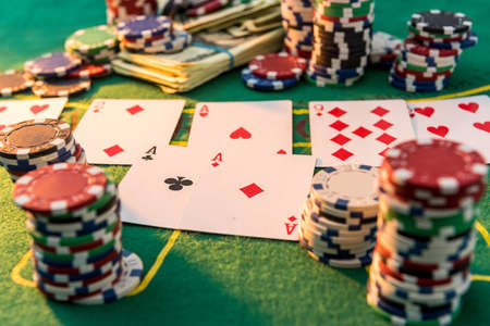 Diferent about cost poker chips with playing cards and american dollars on greent casino table....