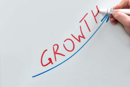 Hand drawing graph with blue marker. Businessman drawing magnifying arrows oven business graph. Grow.の写真素材