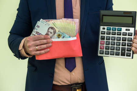businessman in suit hold calculator and lot of ukraine money, UAH, grivnya, isolated on greenの写真素材