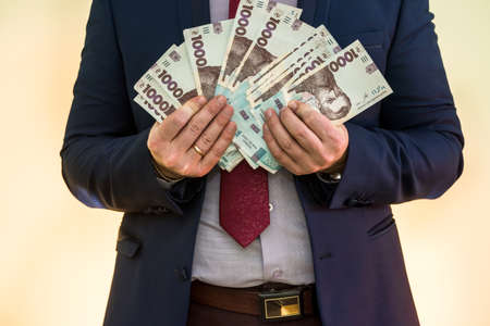 businessman made huge profits, showing a lot of money. a man in a suit holds a pack of new banktons of Ukraine. 1000 hryvniaの写真素材