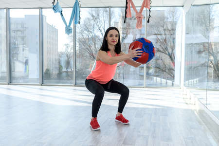 Woman making exercises with ball before mirror in gym