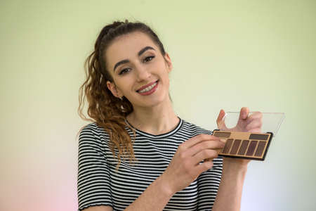 portrait of beautiful young woman holding make-up brush for makeup morning before work. concept of beauty and healthの写真素材
