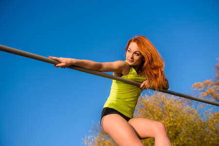 Young fit female training do exercises outdoor on sky background.