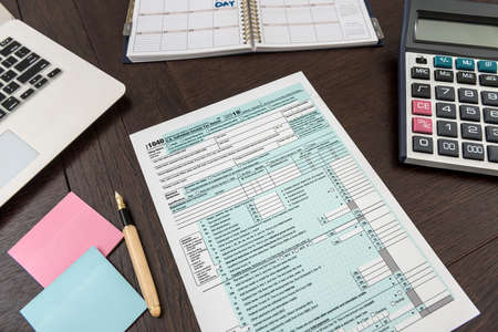 Finance tax form with calculator, laptop and pen. Sticker need help. Accounting time