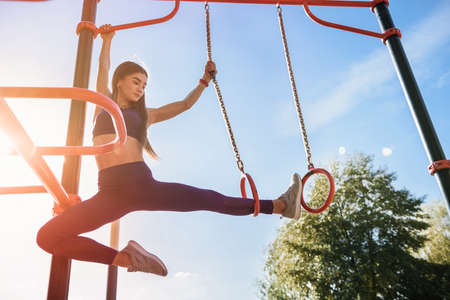 fit young female doing pull ups exercises on crossbar outdoors. Sport and healthy lifestyle concept.