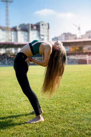 pretty woman athlete stretching her body at stadium grass.の写真素材