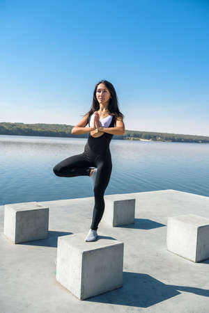 Sportive woman doing yoga exercise in the park, near the lake at daytime. Healthy lifestyle conceptの写真素材