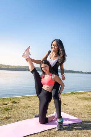 young slim women doing stretching exercise relaxing and warm up after jogging and running in park near lake, morning time. Concept of wellness and healthy lifestyleの写真素材