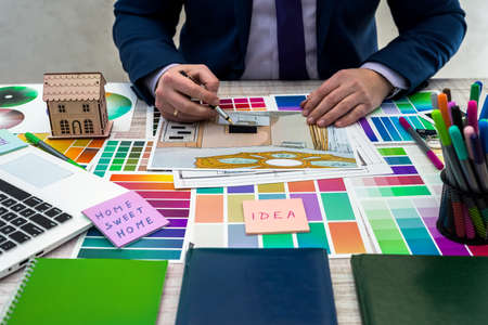 Designer develops a sketch of interior illustration with color scheme of material on a table, office workplace. Desktop of an architect and interior designer with samples of equipment and materialsの写真素材