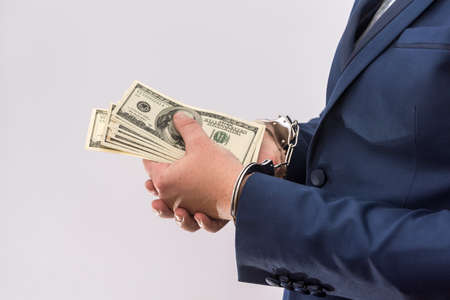 Man in handcuffs holding dollar banknotes isolated, close up. Arrest