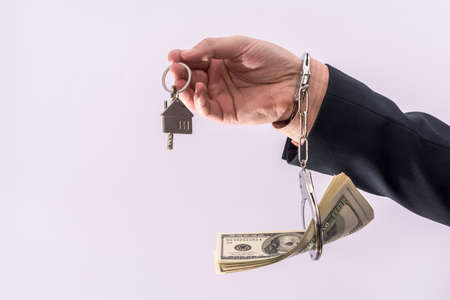 Man in suit hold dollar and house key in handcuff. Bribe corruption conceptの写真素材