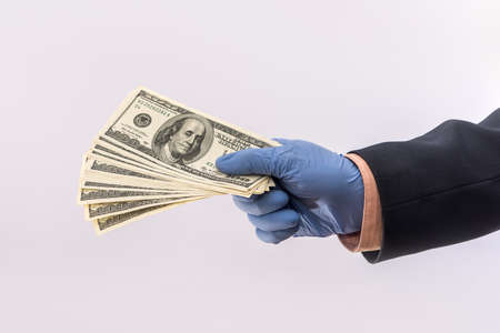 male hand give dollar to pay in protective gloves for safety isolated on white background. medical concept covid 19 coronavirusの写真素材