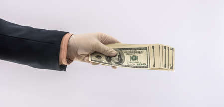 Hands in medical gloves holding stack dollars for safety, dirty money epidemic. All for healthの写真素材