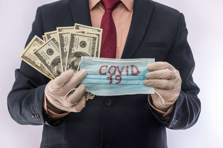 Male's hands in medical gloves give 100 dollar bills for medical masks. Quarantine, for protection against ncovid19の写真素材