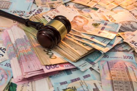 wooden hammer on ukraine money as background. 500 and 1000 new uah grivna. legal or save concept