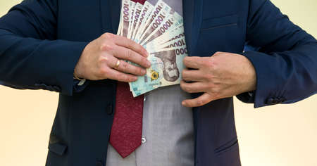 businessman takes a pack of Ukrainian money as a bribe and hides in his pocket in a jacket....