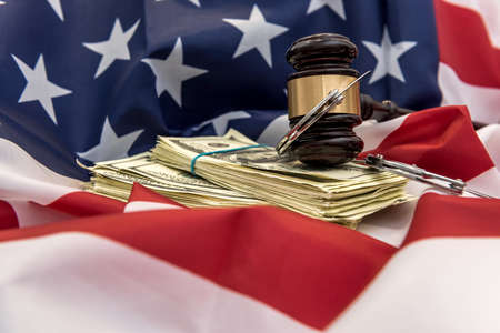Judge's gavel with handcuffs and dollar bills above flag od america. law or crime concept. Justiceの写真素材