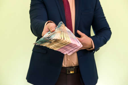 Young businessman holding huge amount of money. New ukraine UAH banknotes 1000 and 500 in the hands of a businessman. Profit.の写真素材