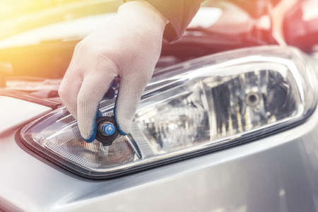 the mechanic replaces the halogen bulbs in the headlights in the car. auto technologyの写真素材