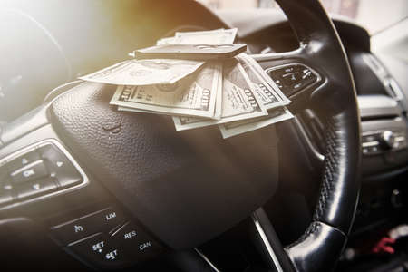 100 dollar bills with car key inside car. bribe or buy rent concept. cash into autoの写真素材