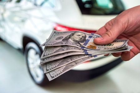 Man give dollar as payment for the purchase or repair of a car. Concept of purchase new modern carの写真素材