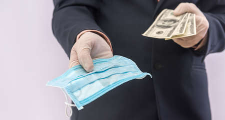 Male hands in medical gloves hold dollar banknotes and protective medical mask, safety covid19....