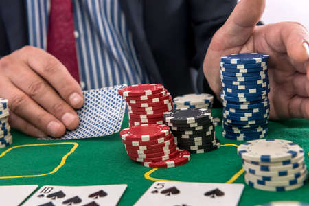 man play in casino with playing cards and chips at green table. gambling