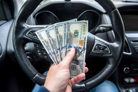 man gives dollars while sitting in the car. concept of shopping, money