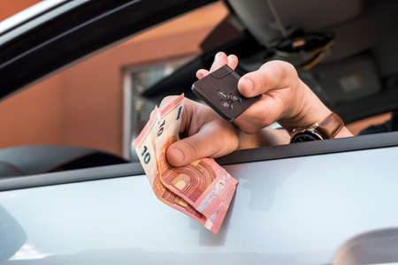 male's hand holding euro bills and key inside car for buy or rent. finance