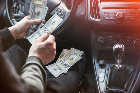 man in his car count us money bills for pay. finance concept