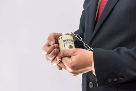 Man in handcuffs holding dollar banknotes isolated, close up. Arrest