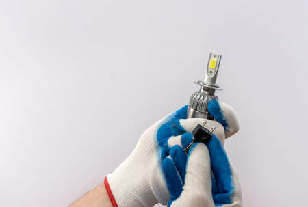 hand in protective glove holding led halogen headlight bulb,isolated