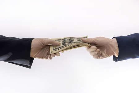 sharing dollars between two businessman for pay goods in medical gloves, isolated on white background. coronavirus pandemic periodの写真素材